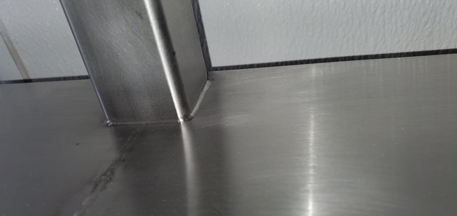 Brushed stainless steel surface with a finished corner seam