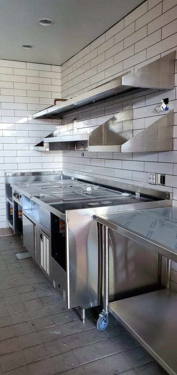 Stainless wall hood and work table installed against white subway tile