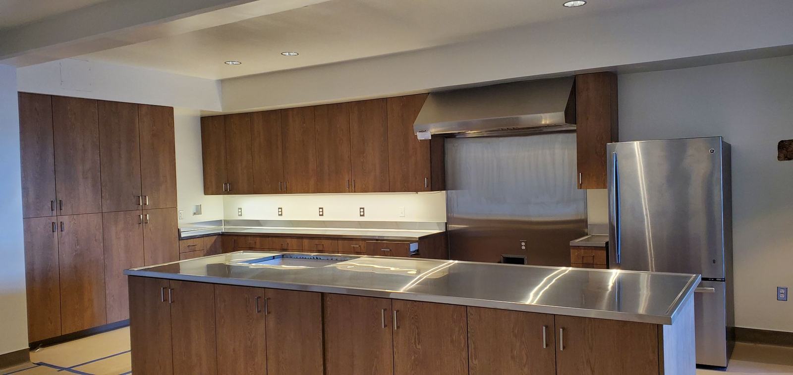 Finished kitchen with a stainless steel island, wood cabinets and a wall hood
